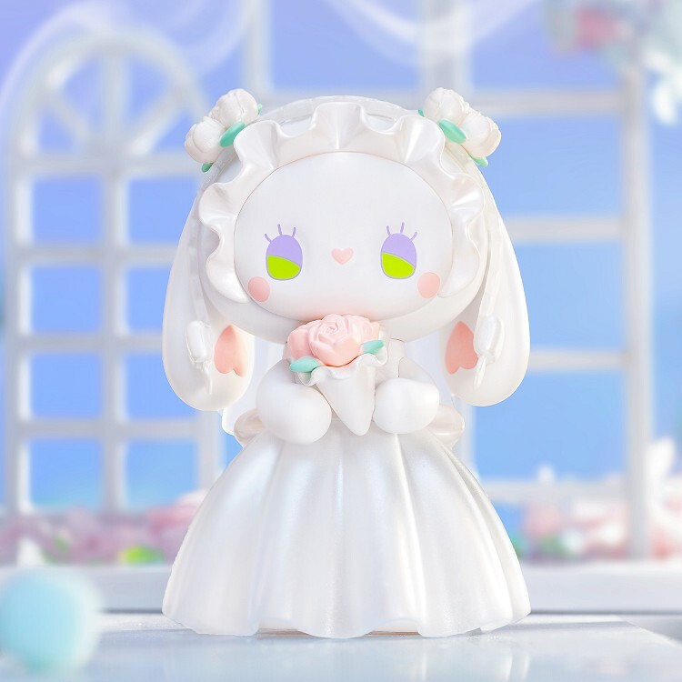 The Lucky Emma Secret Forest Wedding blind box features a cute white figurine in a wedding dress holding a pink rose, with heart-shaped cheeks and fluffy ears, from the Lucky Emma brand, posed before a vibrant decorative background.