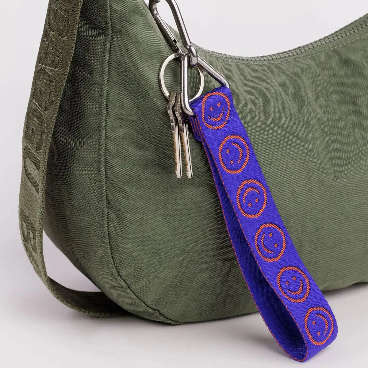 Baggu logo keychain with blue smiley strap, orange pattern, metal ring and clips attached to bag