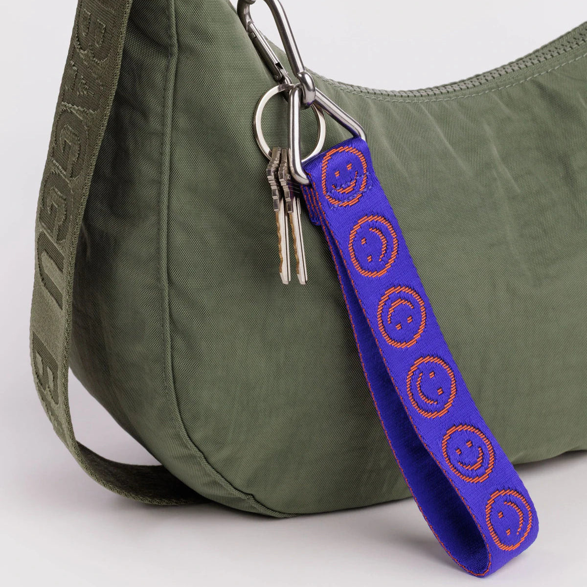 Baggu logo keychain with blue smiley strap, orange pattern, metal ring and clips attached to bag