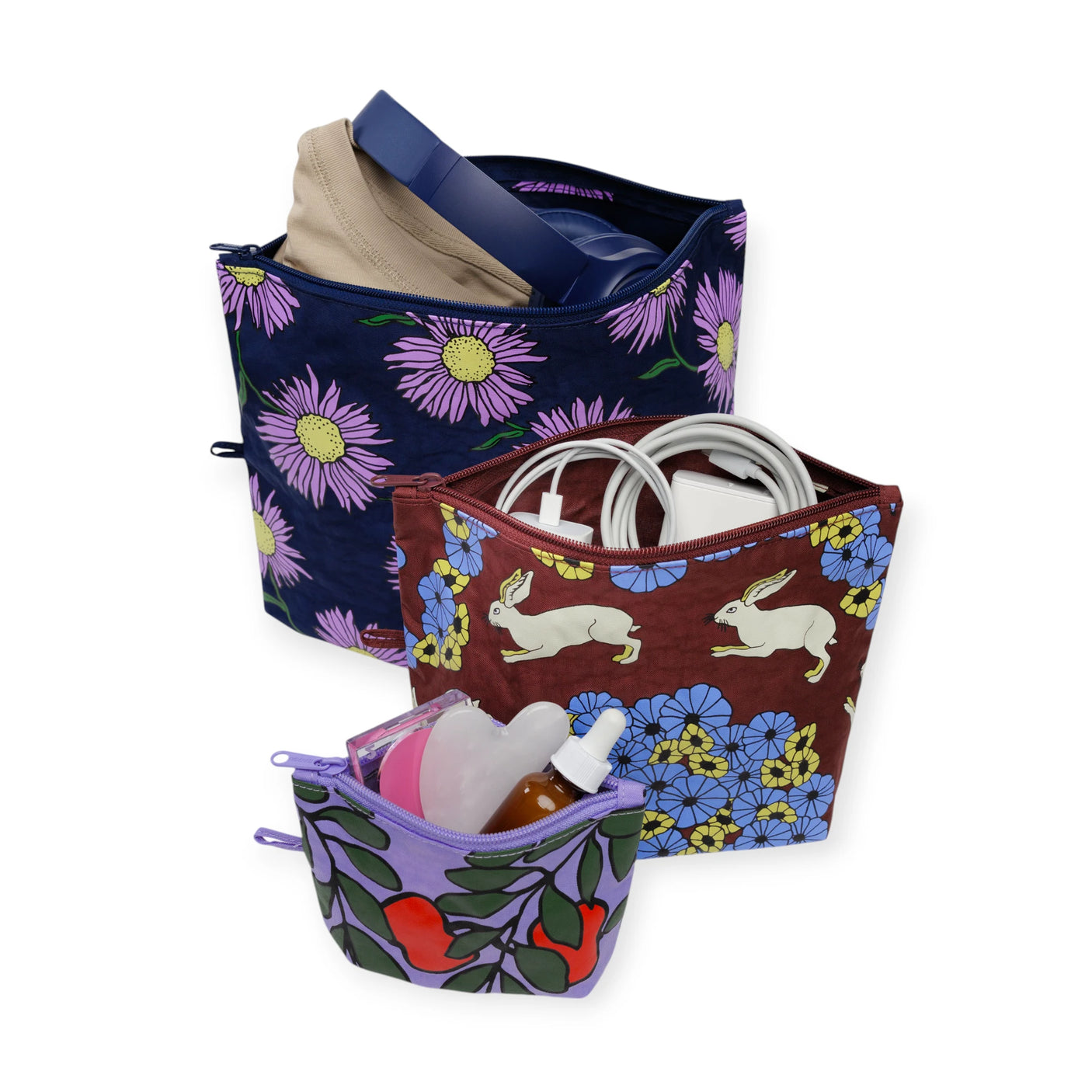 Set of three colorful Baggu Go pouches with floral and rabbit prints, filled with everyday essentials and tech items.