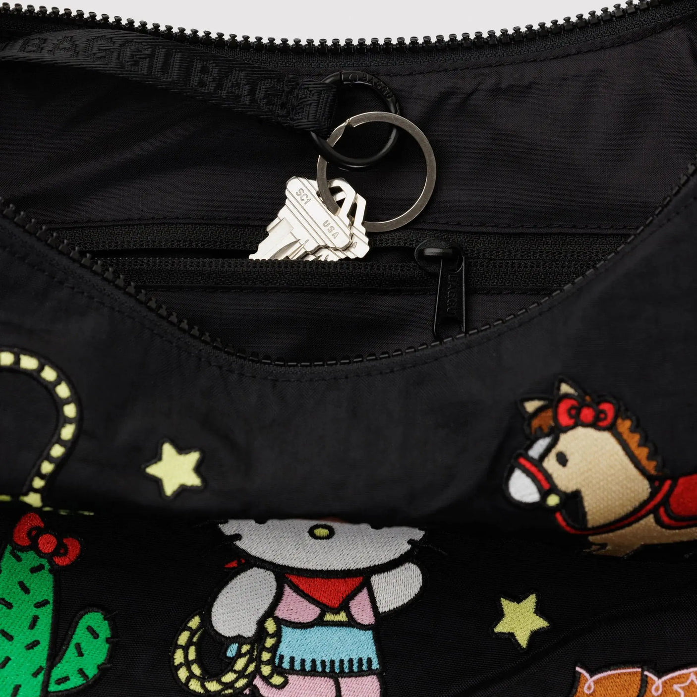Black crescent bag with zippered opening and metal ring key fob detail