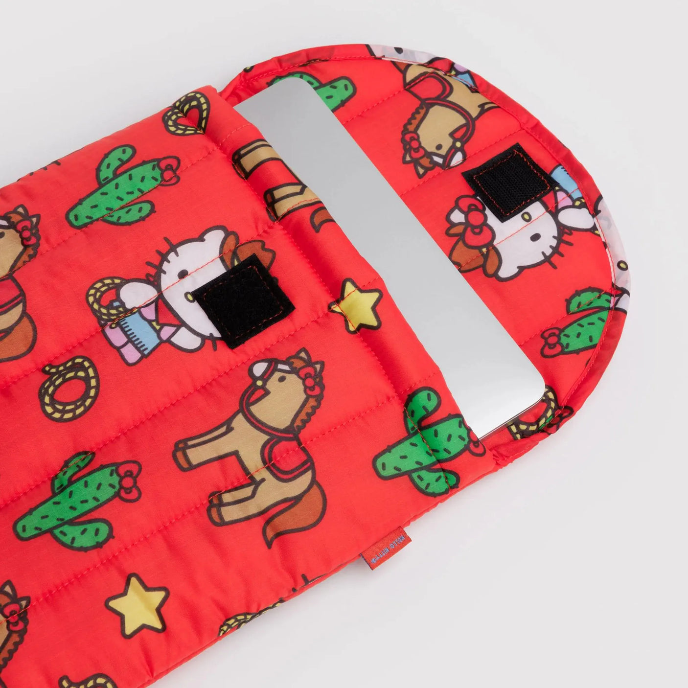 Red puffy laptop sleeve with western Hello Kitty print and black patch details
