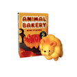 A toy box labeled "Animal Bakery Blind Box - Vol 2" from Dreams Inc sits next to a small, lion-shaped figure that looks like a safari-themed treat.