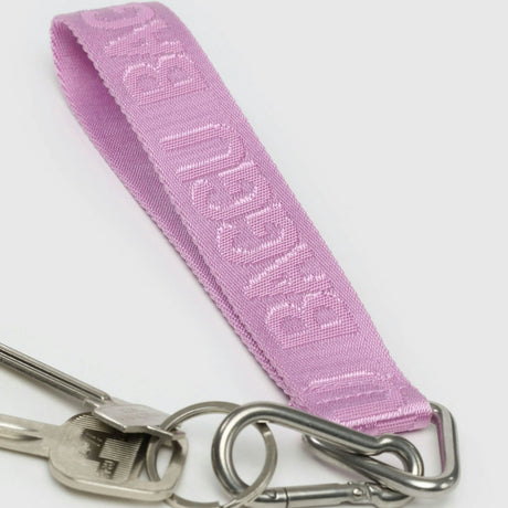 A Baggu Logo Keychain in Peony, crafted from recycled nylon webbing, features "MIGUEL BIAS" and is attached to metal keys with a silver clip.