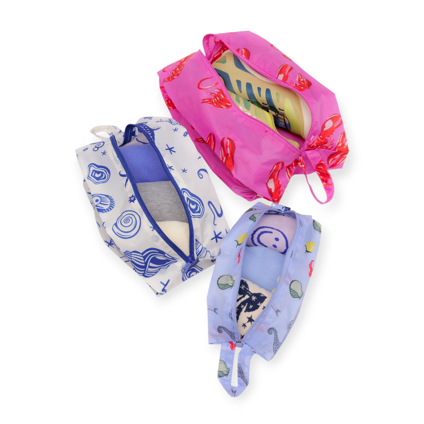 Baggu Storage & Travel Set - Sea Creatures by Baggu features three zippered pouches with playful sea creature prints, arranged on a white background and neatly filled with folded clothes.