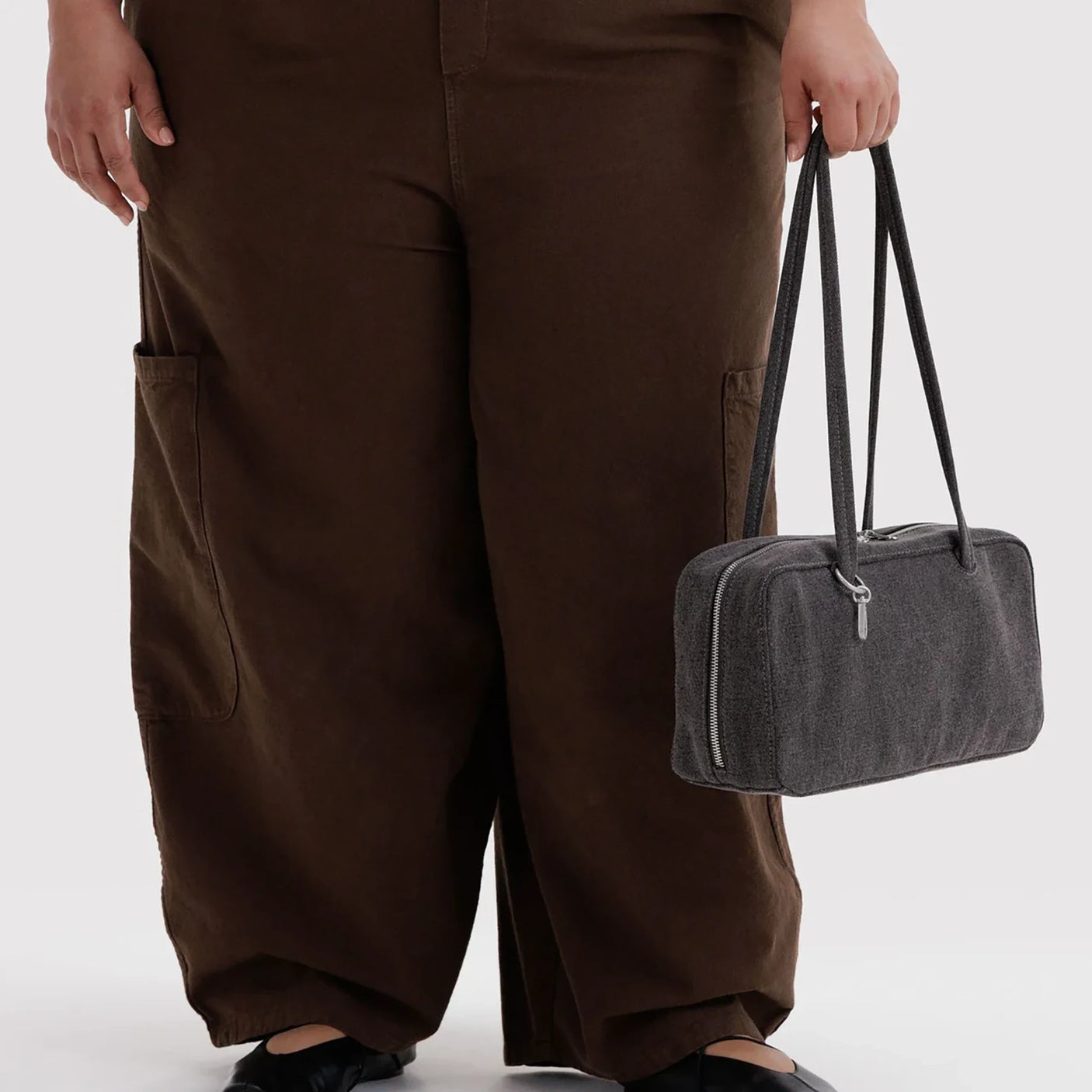 Baggu washed black denim bowler bag held at side, top handles, zip closure.