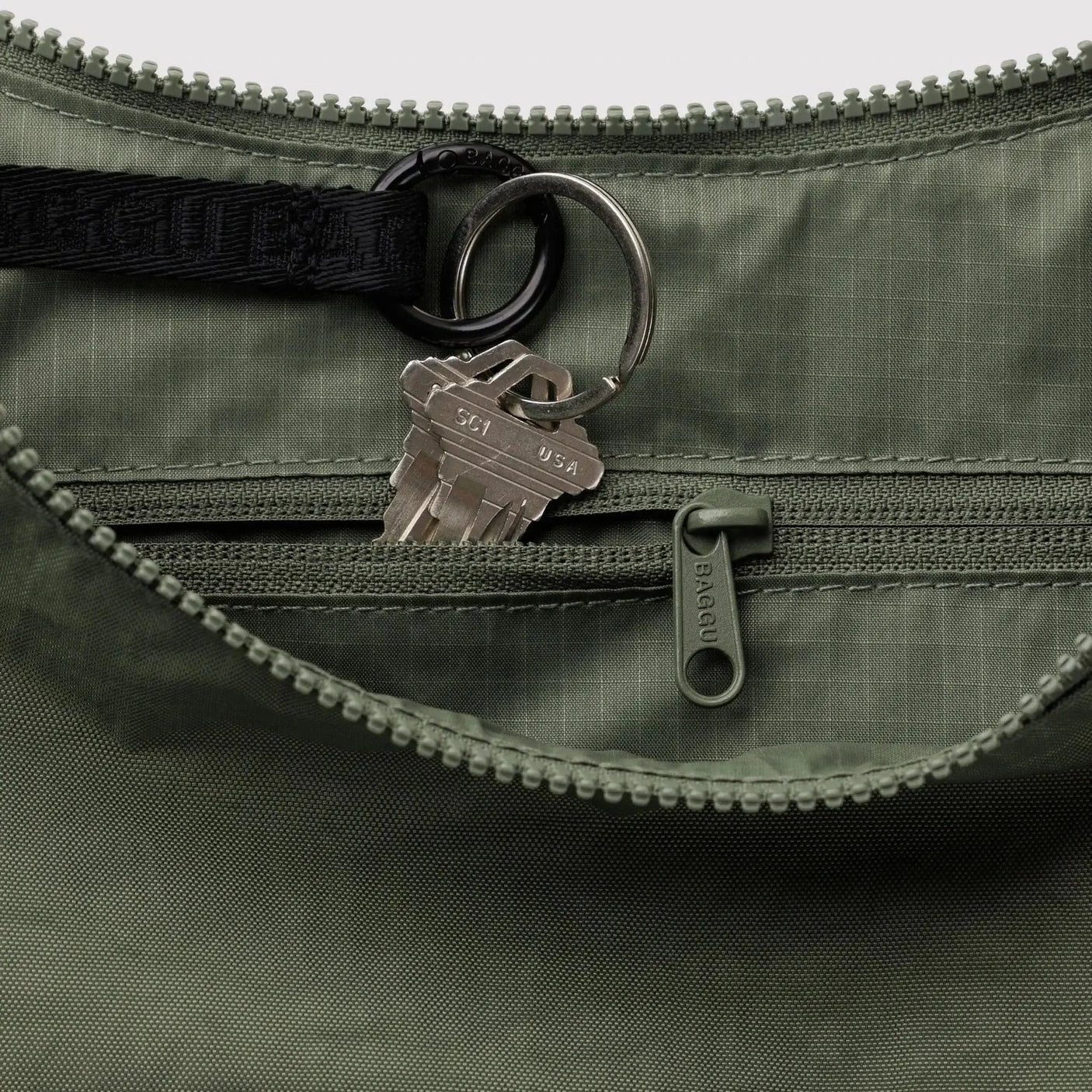 Crescent bag interior close-up with zipper, key ring, and Baggu logo pull tab