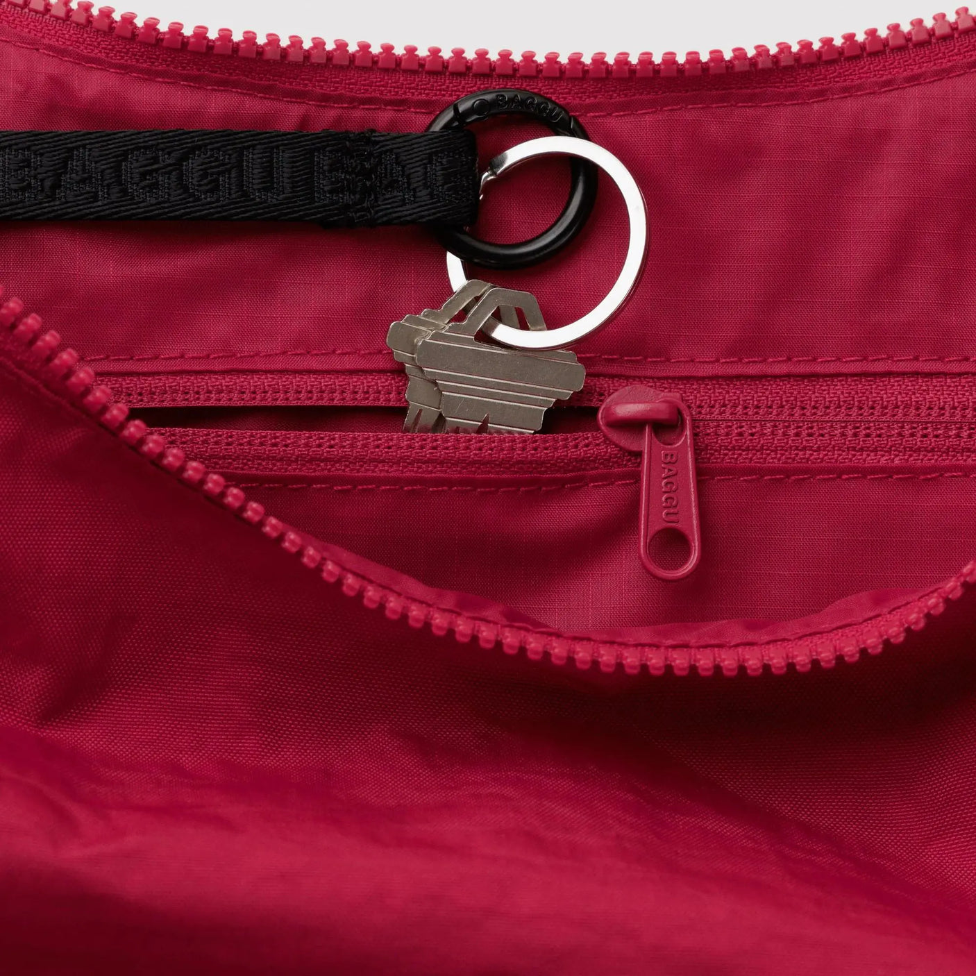 Red nylon crescent bag interior with zipper, key ring, and toggle loop