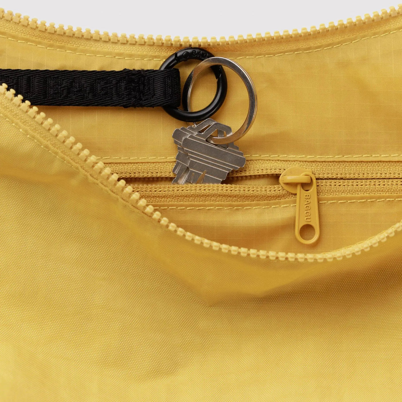 Sunflower yellow nylon crescent bag close-up: zipper pull with black key clip