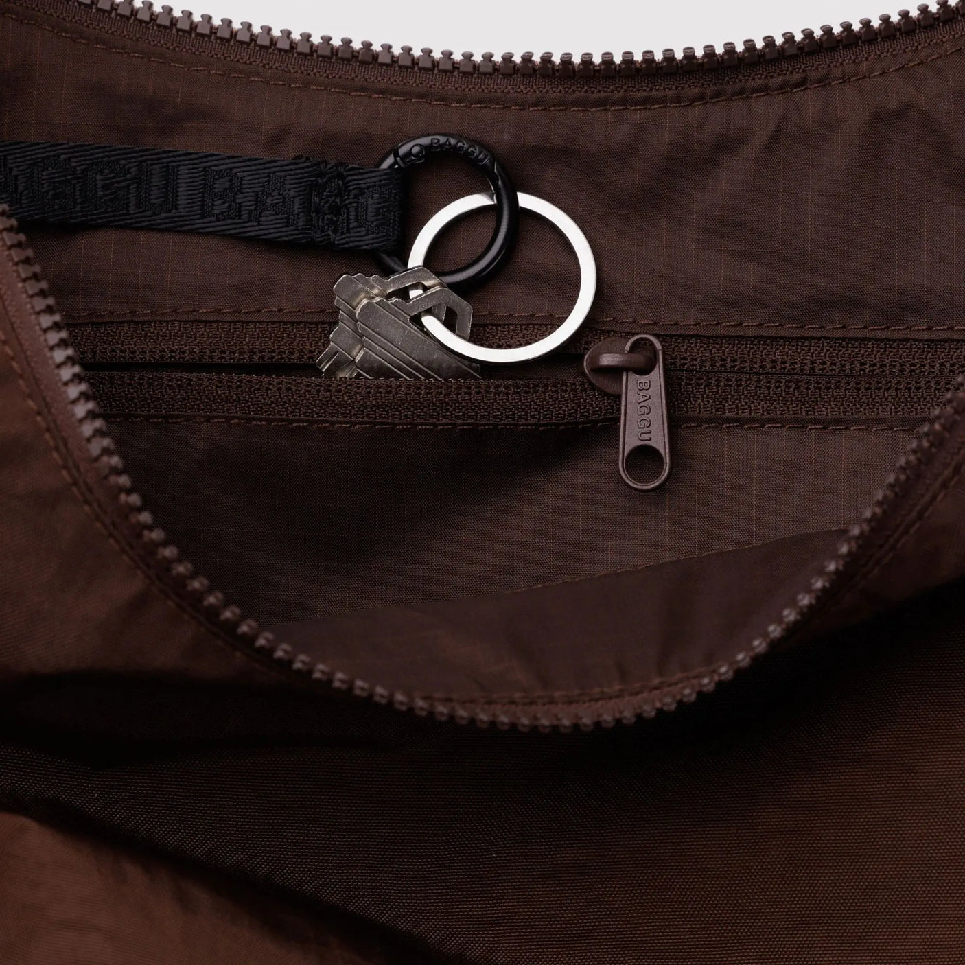 Brown crescent bag interior with zippered opening, ring clip, and dark lining