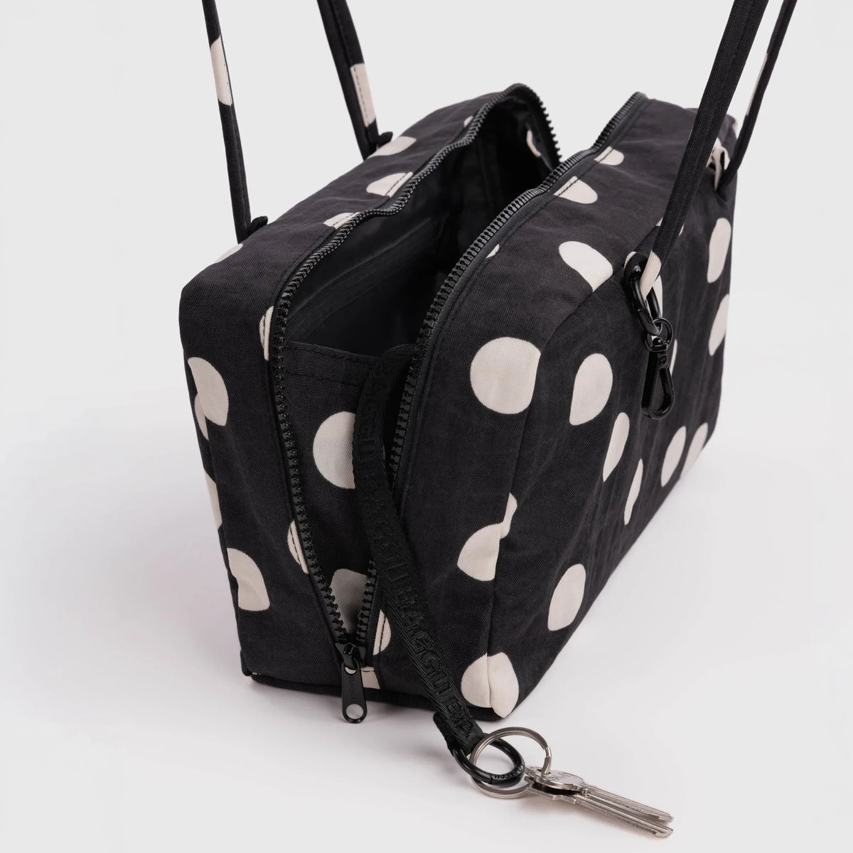 Black nylon bowler bag with cream polka dots, open top showing zippers and key clip.