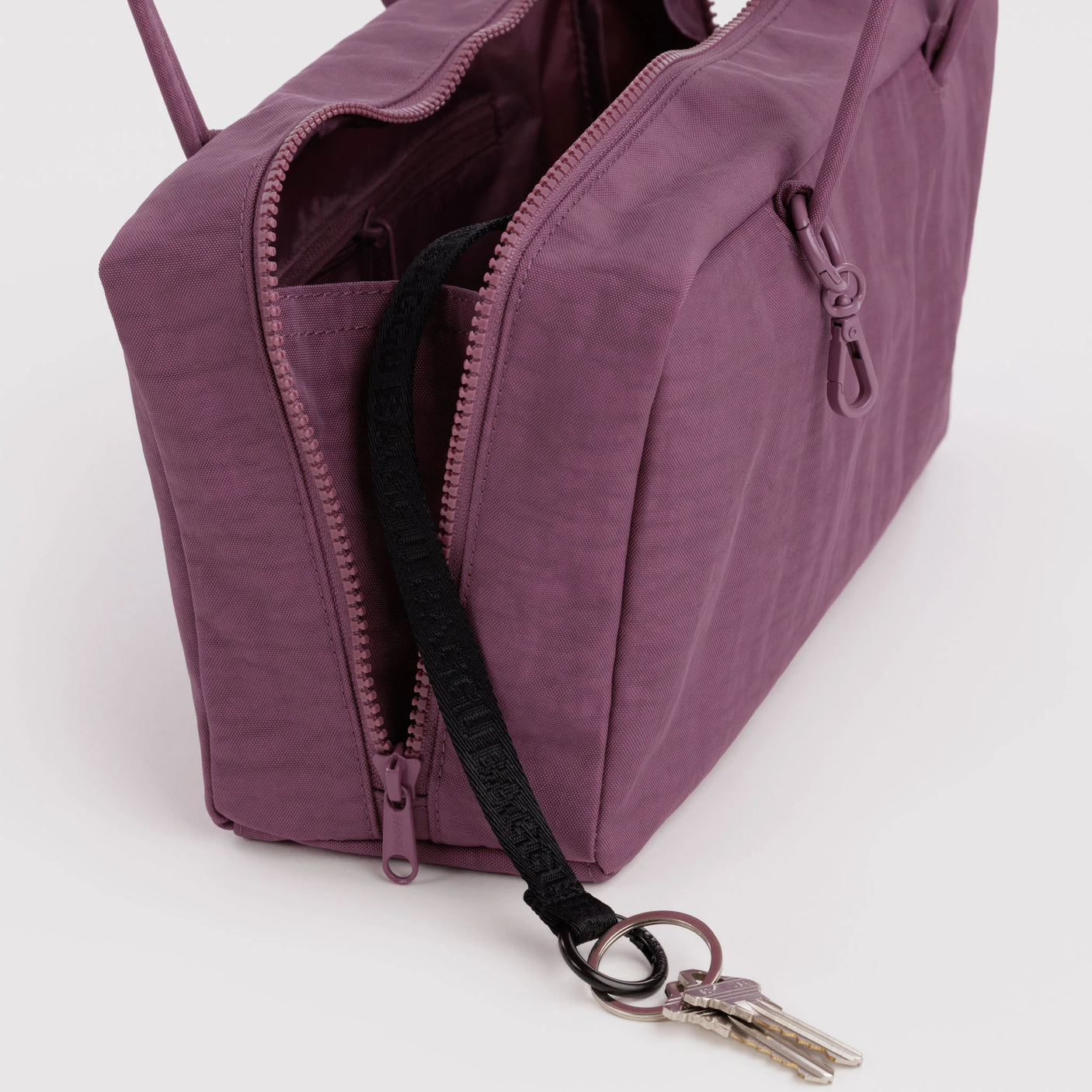 Plum nylon bowler bag close-up: zip pocket, dark lining, key clip