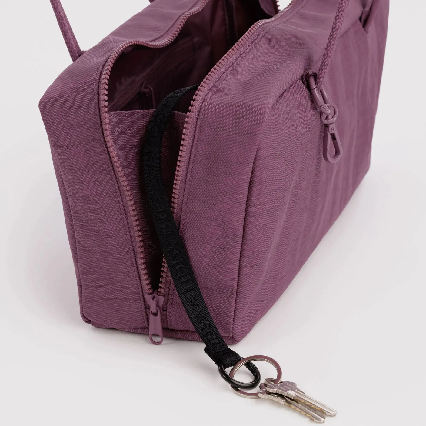 Plum nylon bowler bag close-up: zip pocket, dark lining, key clip