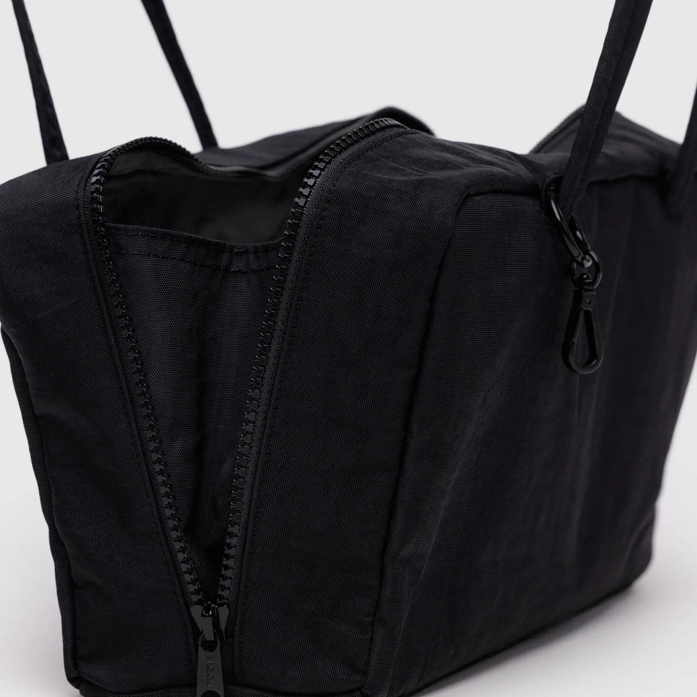 Black nylon bowler bag close-up of zipper and side seams, with top handle