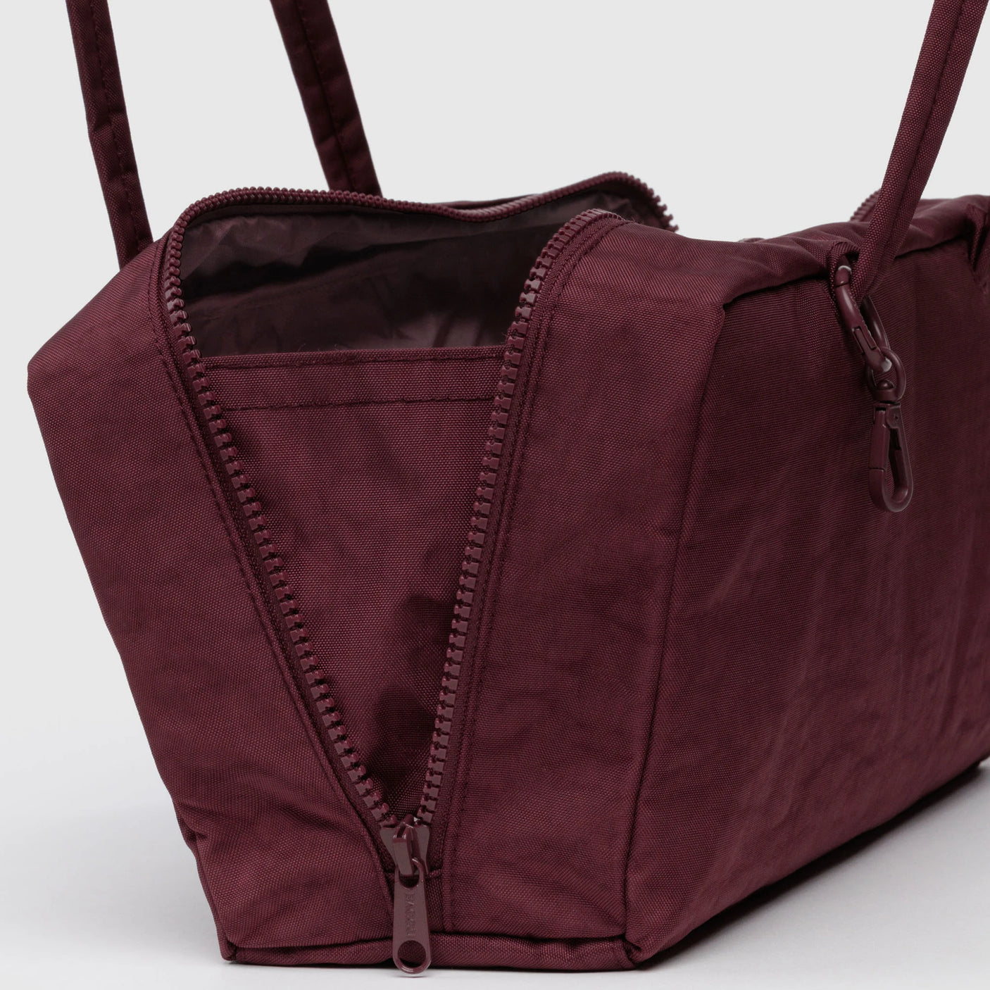 The Baggu Nylon Bowler Bag - Mahogany features a wide-open zipper, revealing its empty, lined interior.