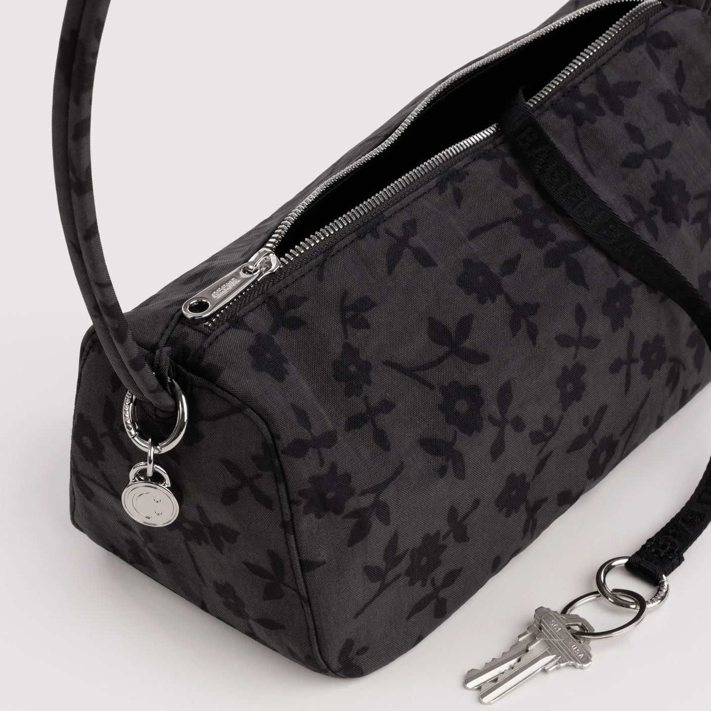 Charcoal nylon bag detail: floral print, metal zipper, key fob on ring