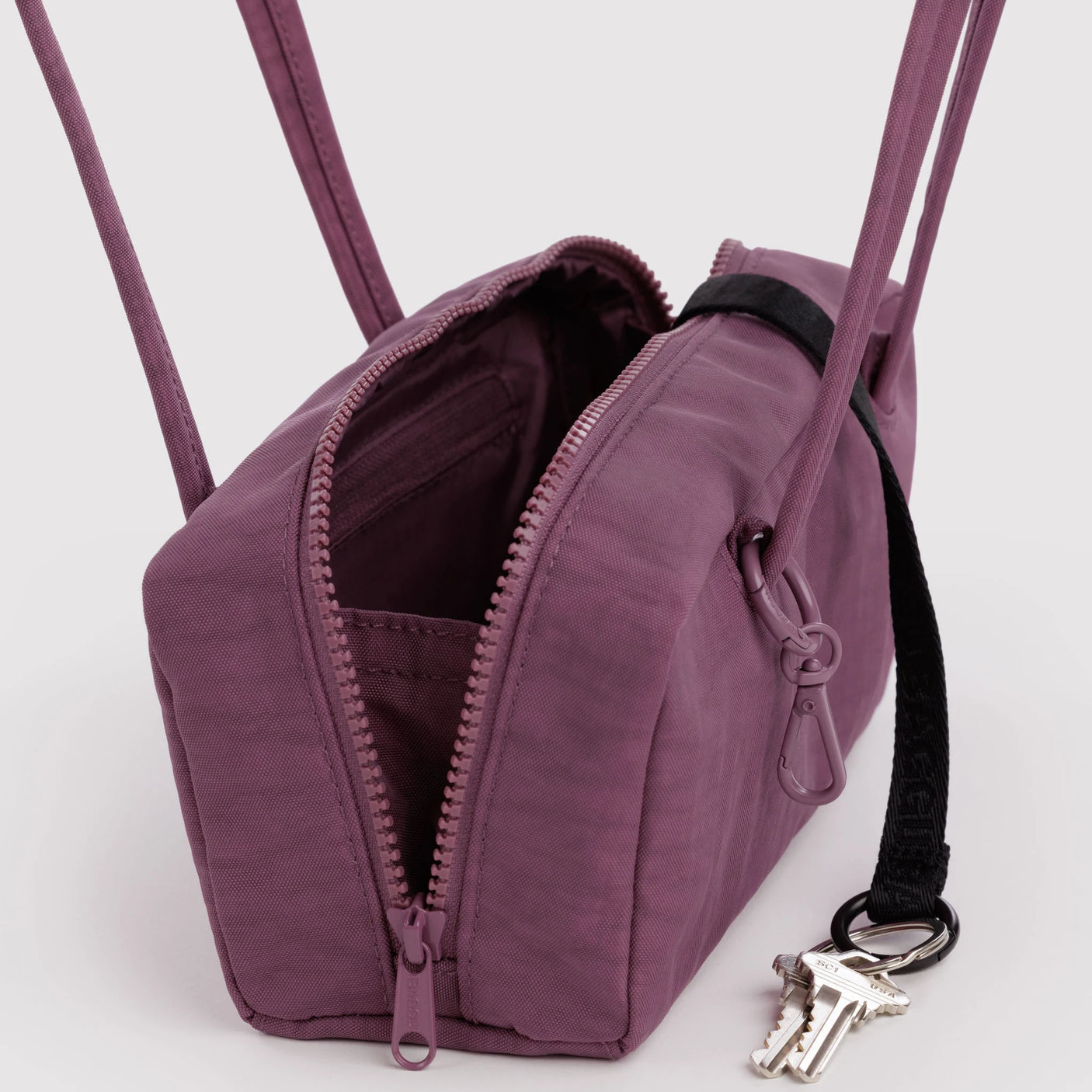 Plum bowler bag with open zipper front, compartments inside, and keyring on side