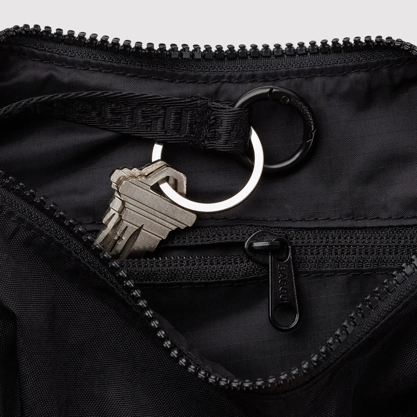Black nylon crescent bag close-up: zipper, key clip, and metal ring