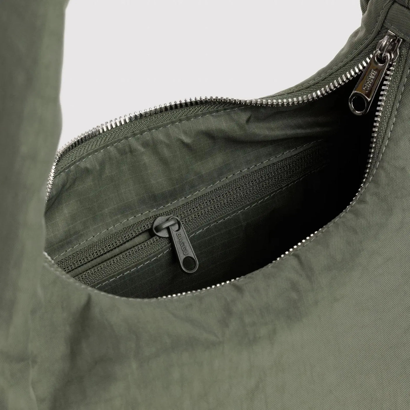 Olive-green nylon bag interior with zippered pocket and metal zipper pull