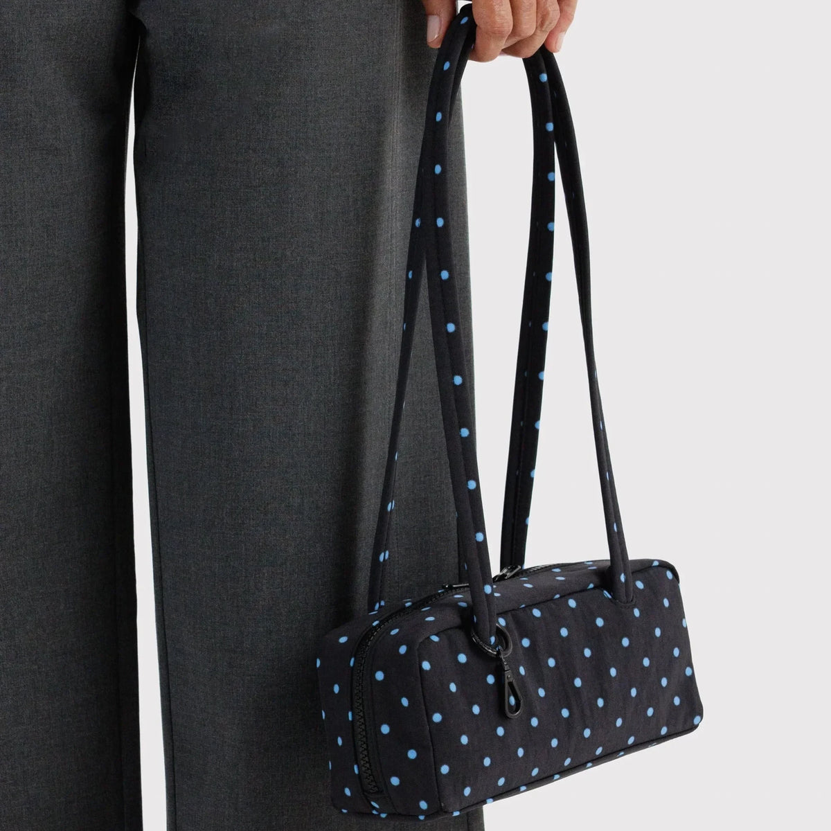 Small bowler bag with black base and sky-blue micro dots, held by a double top handle