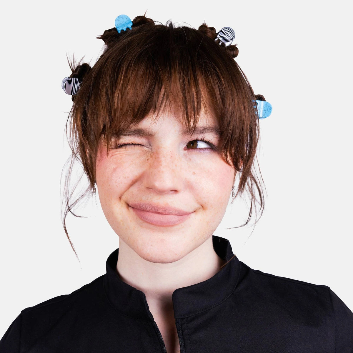 Woman wearing blue micro claw hair clips in a short hairstyle with bangs.