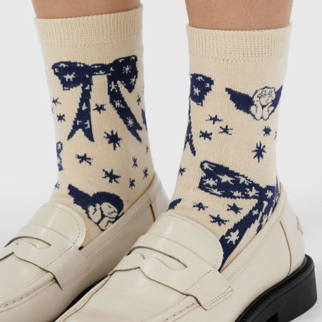 Baggu Crew Socks - Cherub Bows by Baggu feature a beige and blue cherub bow pattern on cream, crafted from a soft bamboo rayon blend—perfectly paired with off-white loafers for a stylish look.
