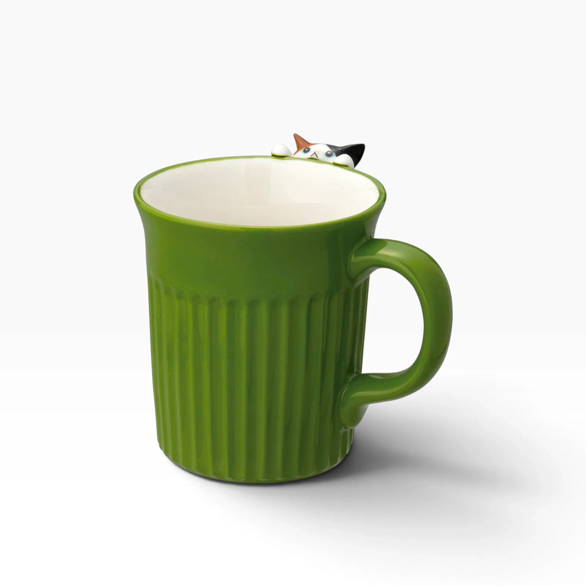 Green ceramic mug with white interior and small calico cat figure peeking from rim