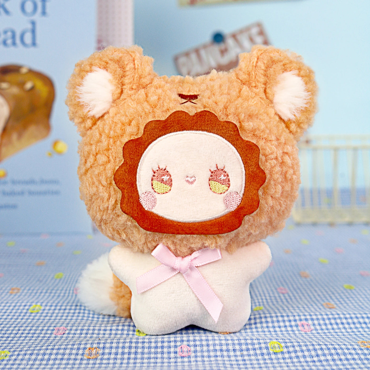 The Emma Fuzzy Family Keychain Blind Box by Lucky Emma features a plush toy with a lion-like face, round ears, and a pink ribbon—perfect as a cute keychain or bag charm.