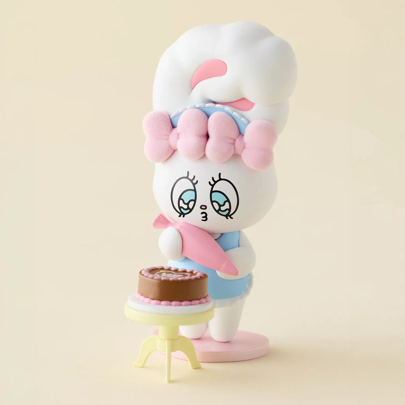 White and pink bunny blind box figure holding baby in pink, with cake accessory