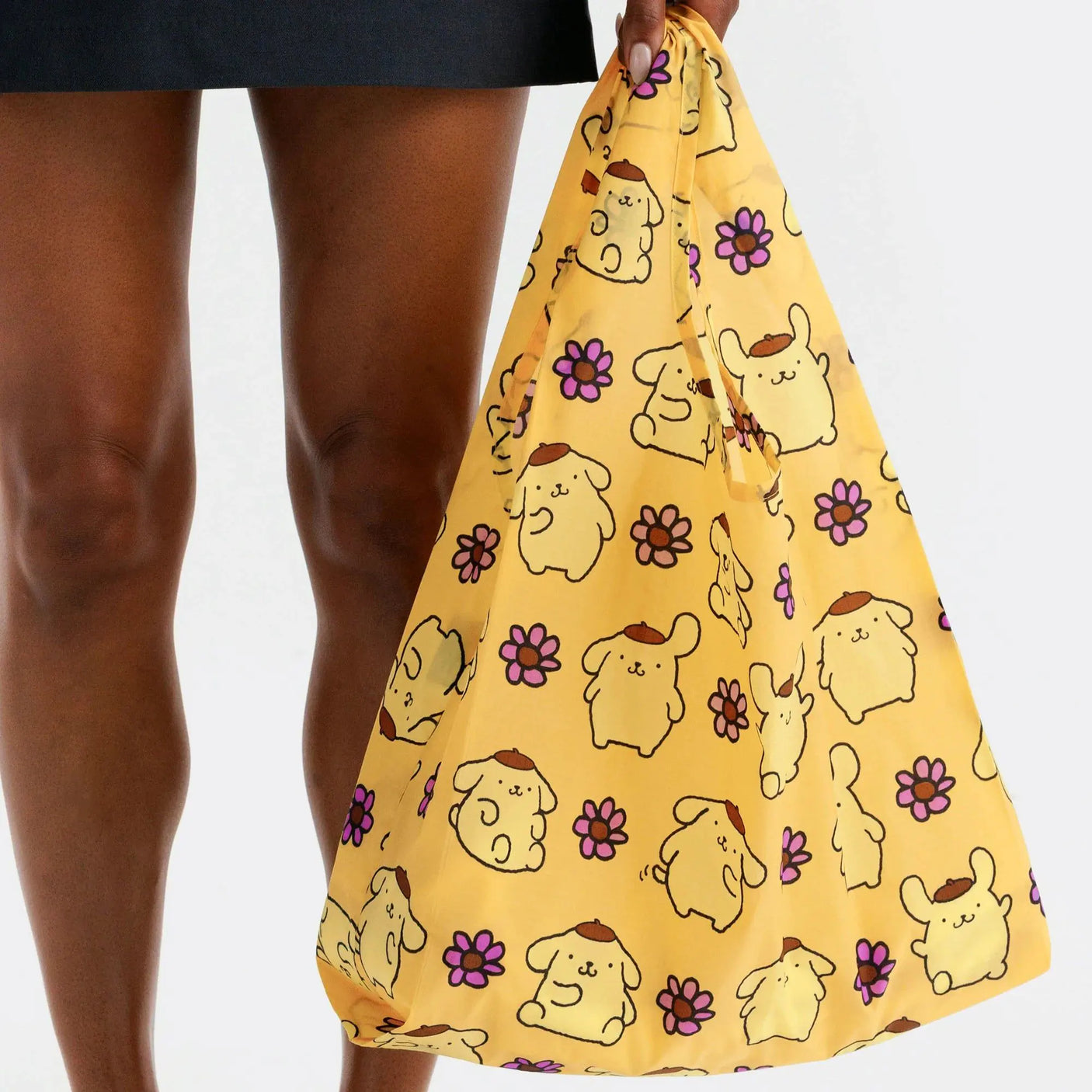 Baggu tote bag held in hand, yellow Pompompurin faces with purple flower print