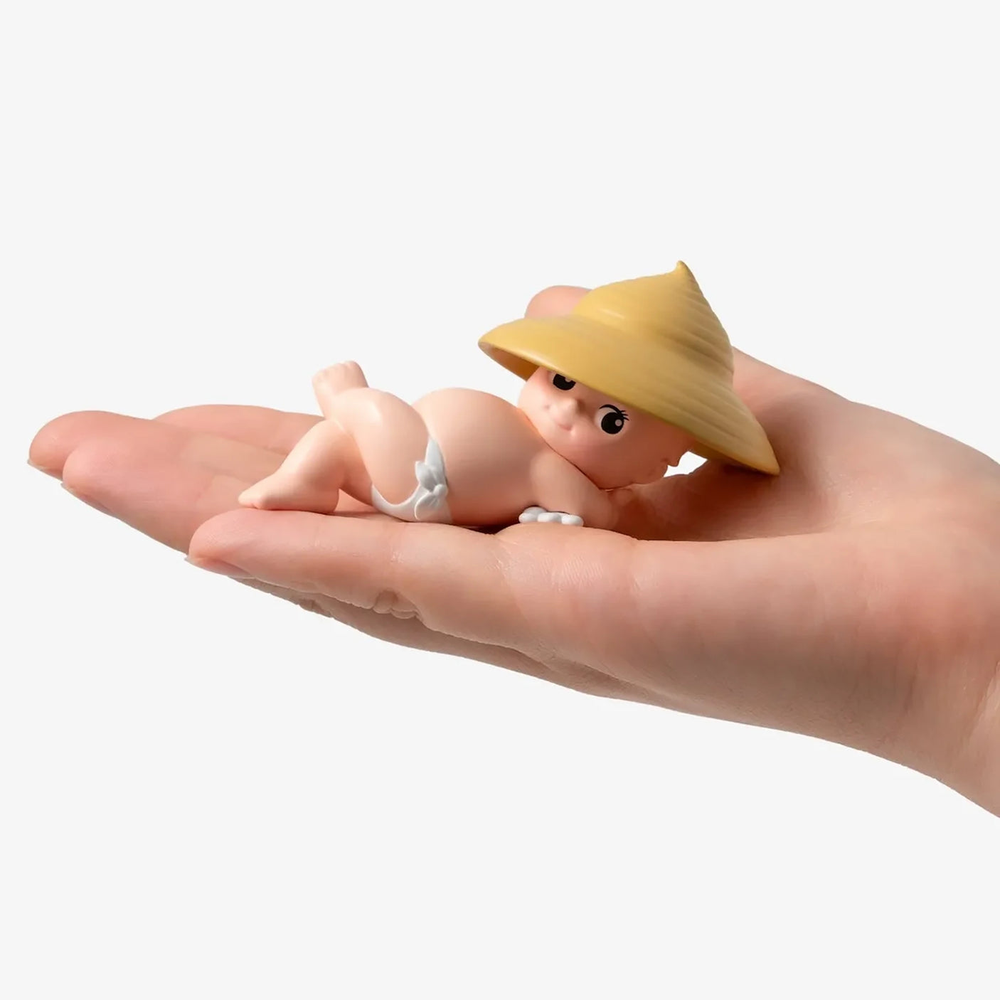 Kewpie In the Garden figurine with a straw mushroom hat, held in a hand
