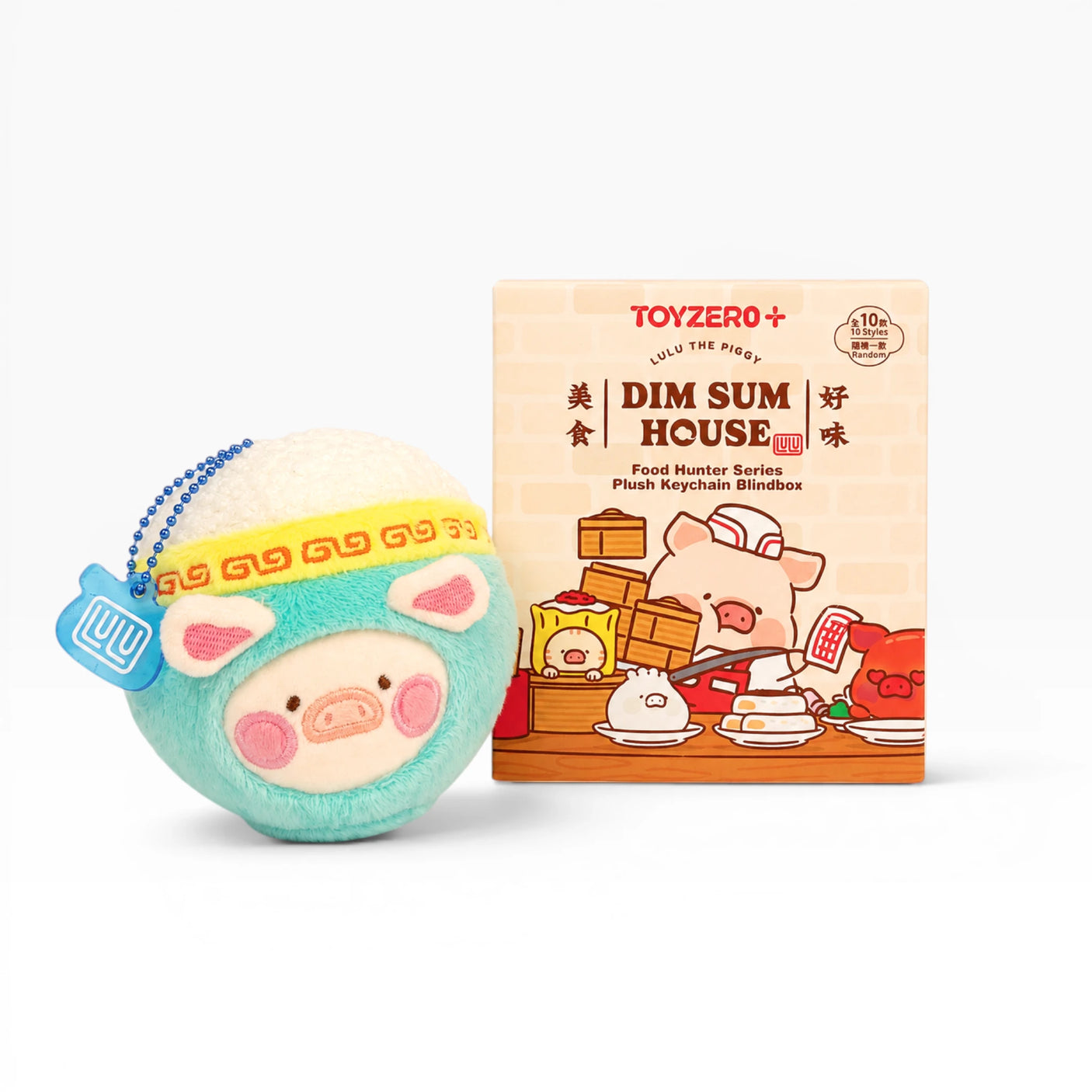 Turquoise pig plush keychain with chain beside Dim Sum House blind box