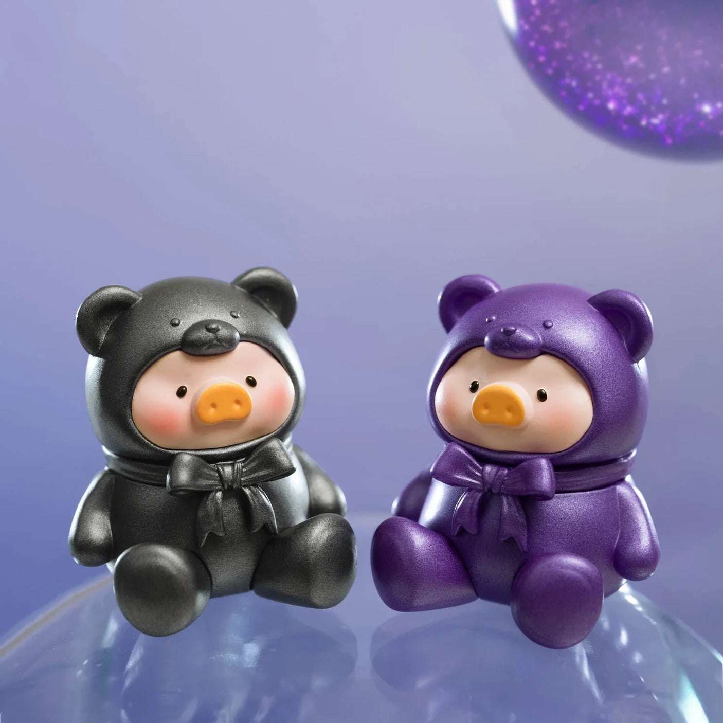 Two LuLu The Piggy - Mini Teddy Blind Bag figurines, dressed in black and purple bear costumes with matching bows, sit on a glossy surface against a blurred purple background—adorable collectibles from LuLu The Piggy.