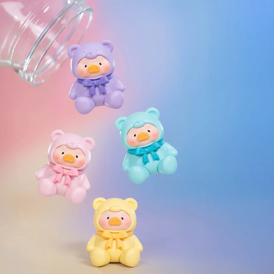 Four pastel LuLu The Piggy figures in bear costumes tumble from a glass jar, resembling surprise collectibles from the LuLu The Piggy - Mini Teddy Blind Bag series, set against a gradient blue and pink background.