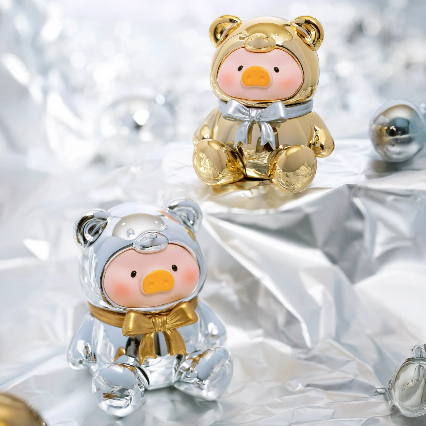 Two LuLu The Piggy - Mini Teddy Blind Bag figurines, dressed in metallic bear suits, stand on a shiny surface with metallic balls scattered around.