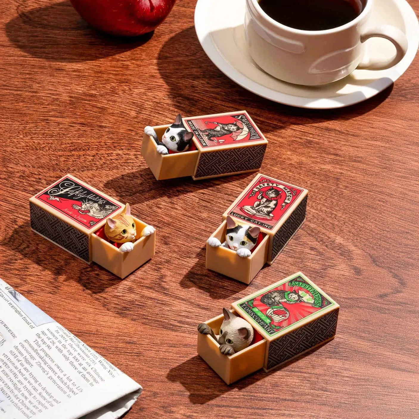 Cat figurines in beige matchbox blind boxes on tabletop, small boxes open.