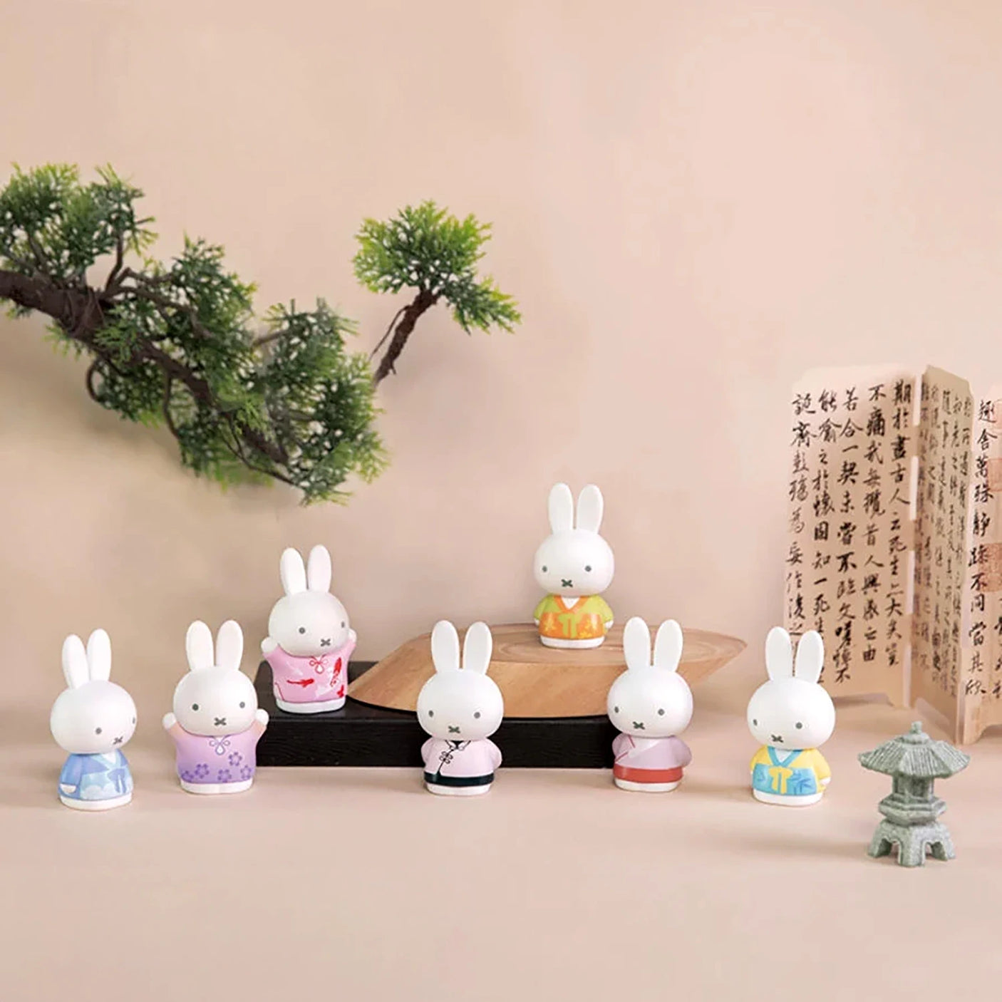 Seven Miffy figures in pastel ancient-style costumes displayed with bonsai and calligraphy scrolls on soft beige background
