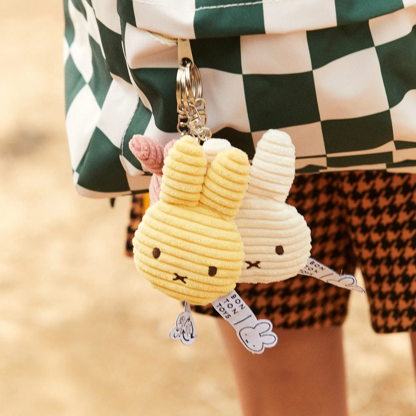 Two white corduroy rabbit keychains with metal rings, one with pink nose