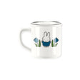 The Miffy Ceramic Mug - Blue Tulip by Miffy features a simple cartoon bunny in a blue outfit with blue tulips on each side. This white ceramic, microwave-safe mug is perfect for everyday use.