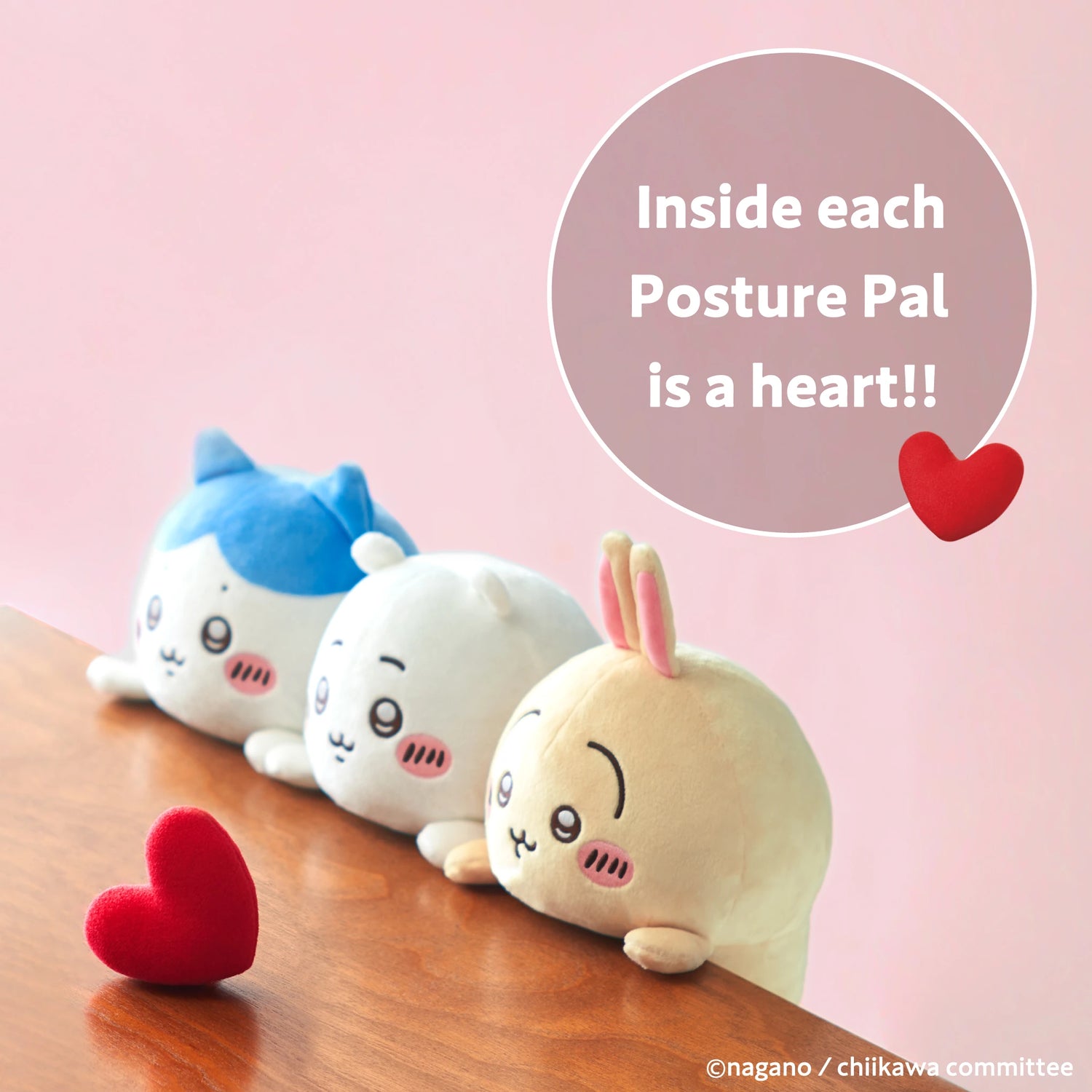 Three Chiikawa Posture Plush Buddy toys from the Chiikawa brand sit on a wooden surface gazing at a red heart. The image says, "Inside each Posture Pal is a heart!!"—a cute and gentle desk companion for posture support.