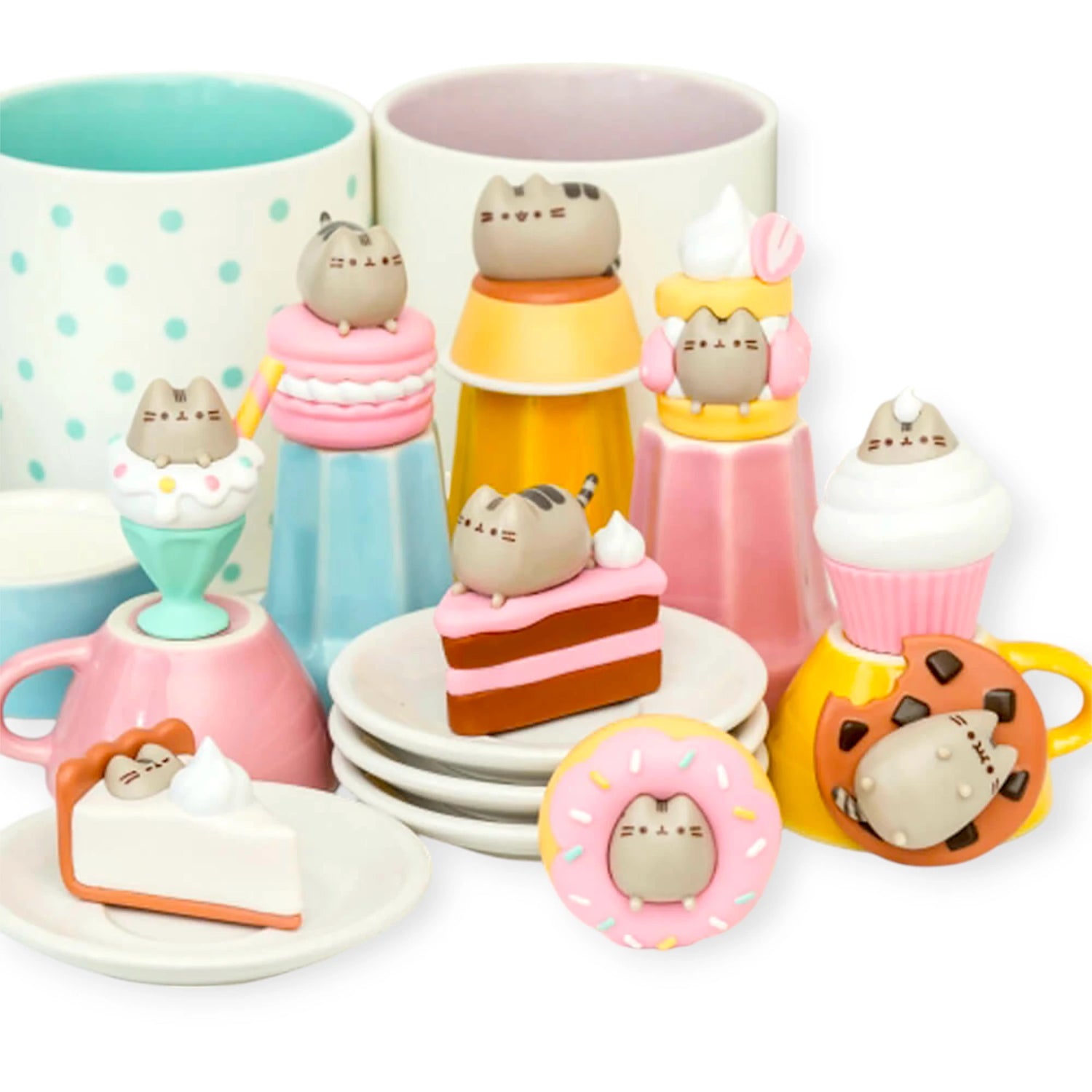 The Pusheen Delicious Desserts - Blind Box figures, styled as cakes, ice cream, and cookies, decorate colorful ceramic mugs and plates.