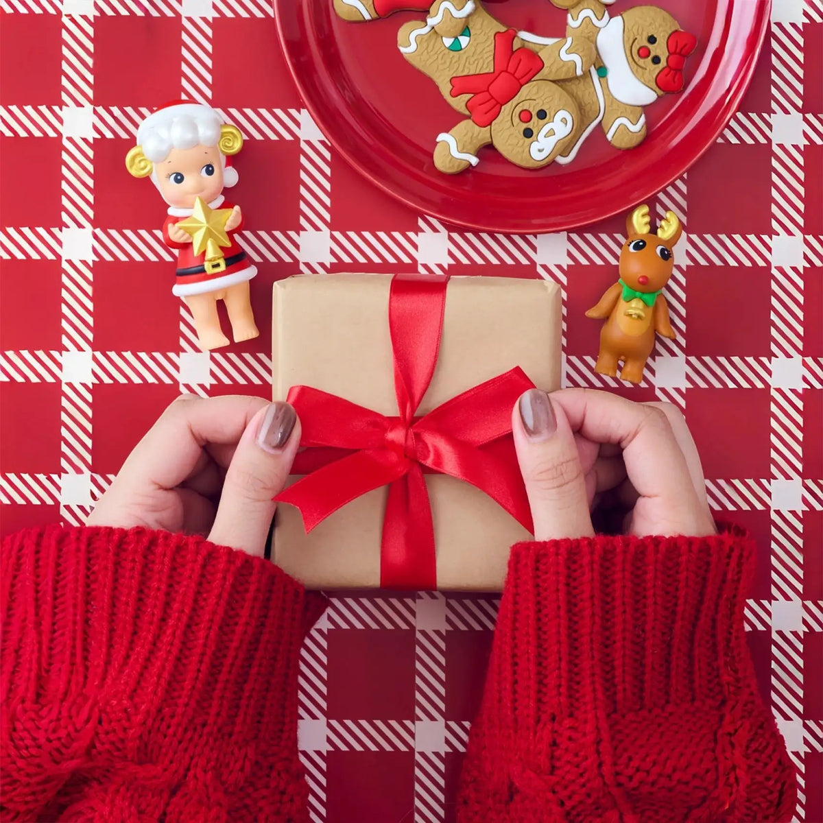 Mini elf and reindeer vinyl figures next to a red ribbon gift box