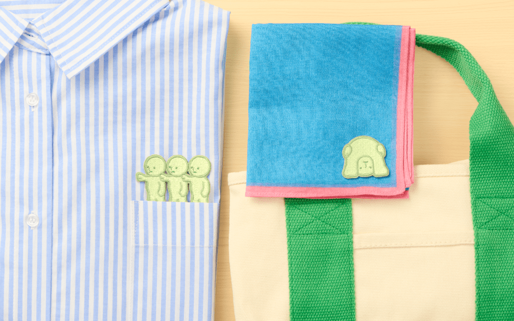 Green Smiski embroidery stickers on folded fabric, including a three-figure group
