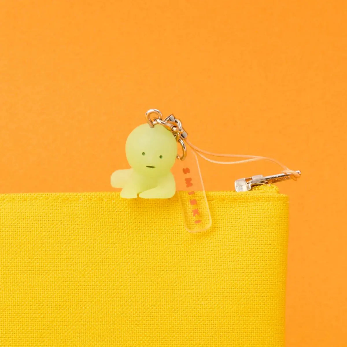 Smiski pale yellow strap keychain charm with seated figure and metal clasp