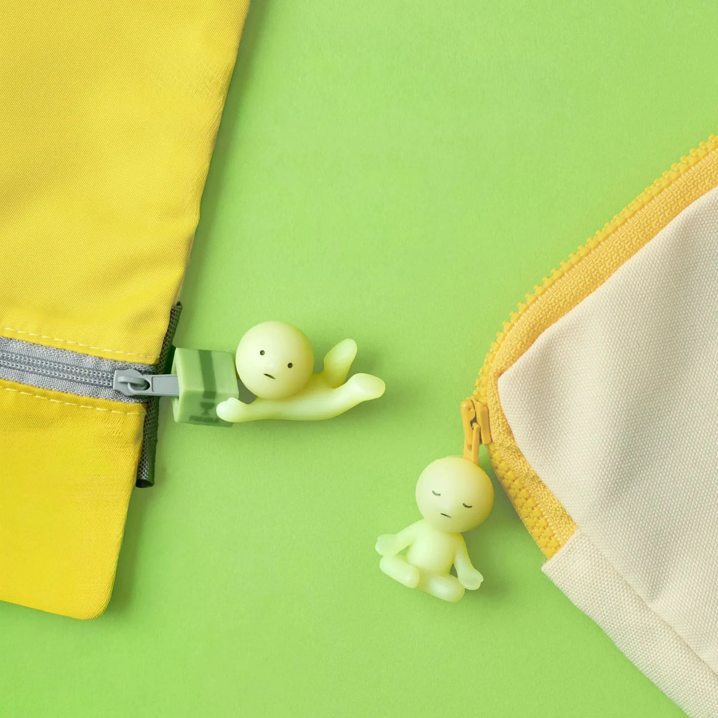 Green Smiski figurines peeking from zipper on yellow and green pouch