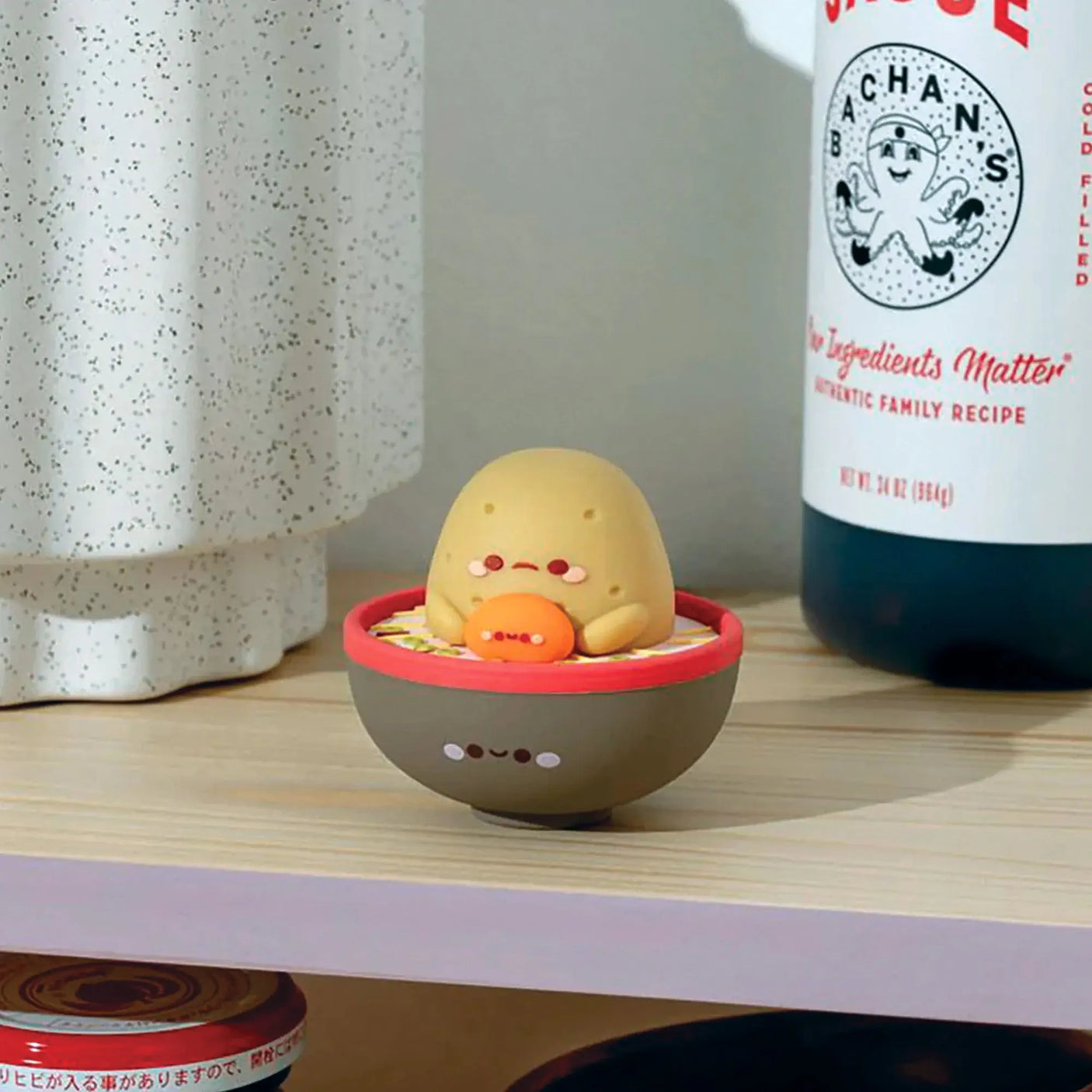 Smoko ramen blind box vinyl figure in red-rimmed bowl on a shelf