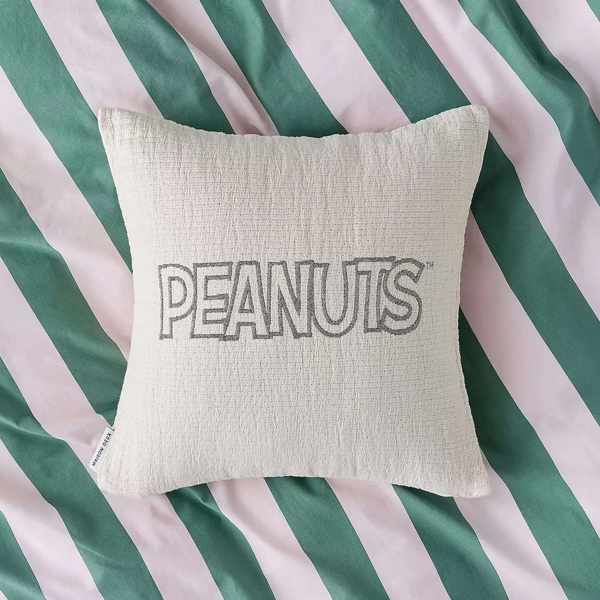 Cream cotton cushion cover with PEANUTS logo centered on front