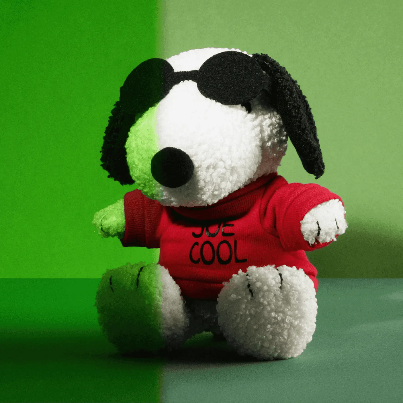 Snoopy plush dog in red Joe Cool sweatshirt, white fur, black ears, seated pose
