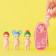 Four small Sonny Angel dolls with unique headgear (strawberry, mouse, cactus, bunny) are displayed next to the Sonny Angel My Bestie Case - Purple by Sonny Angel against a yellow background—ideal for storing or showing off your mini figures.