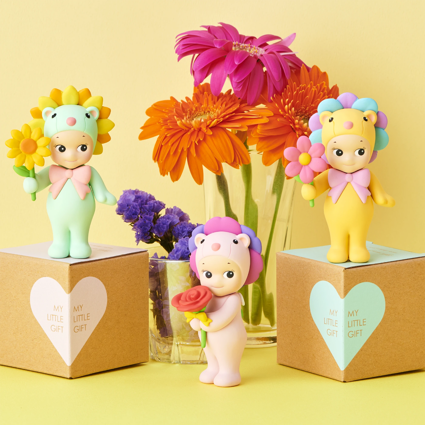 Three pastel-colored mini figures from the Sonny Angel Flower Gift Series by Sonny Angel stand on "My Little Gift" boxes, with colorful flowers in vases—an ideal collectible for fans of the Flower Gift Blind Box series.